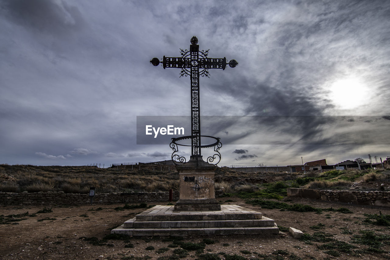 LOW ANGLE VIEW OF CROSS ON FIELD AGAINST CLOUDY SKY
