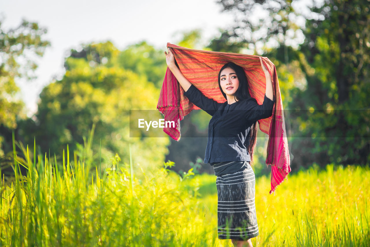 Young woman wearing shawl amidst grassy field