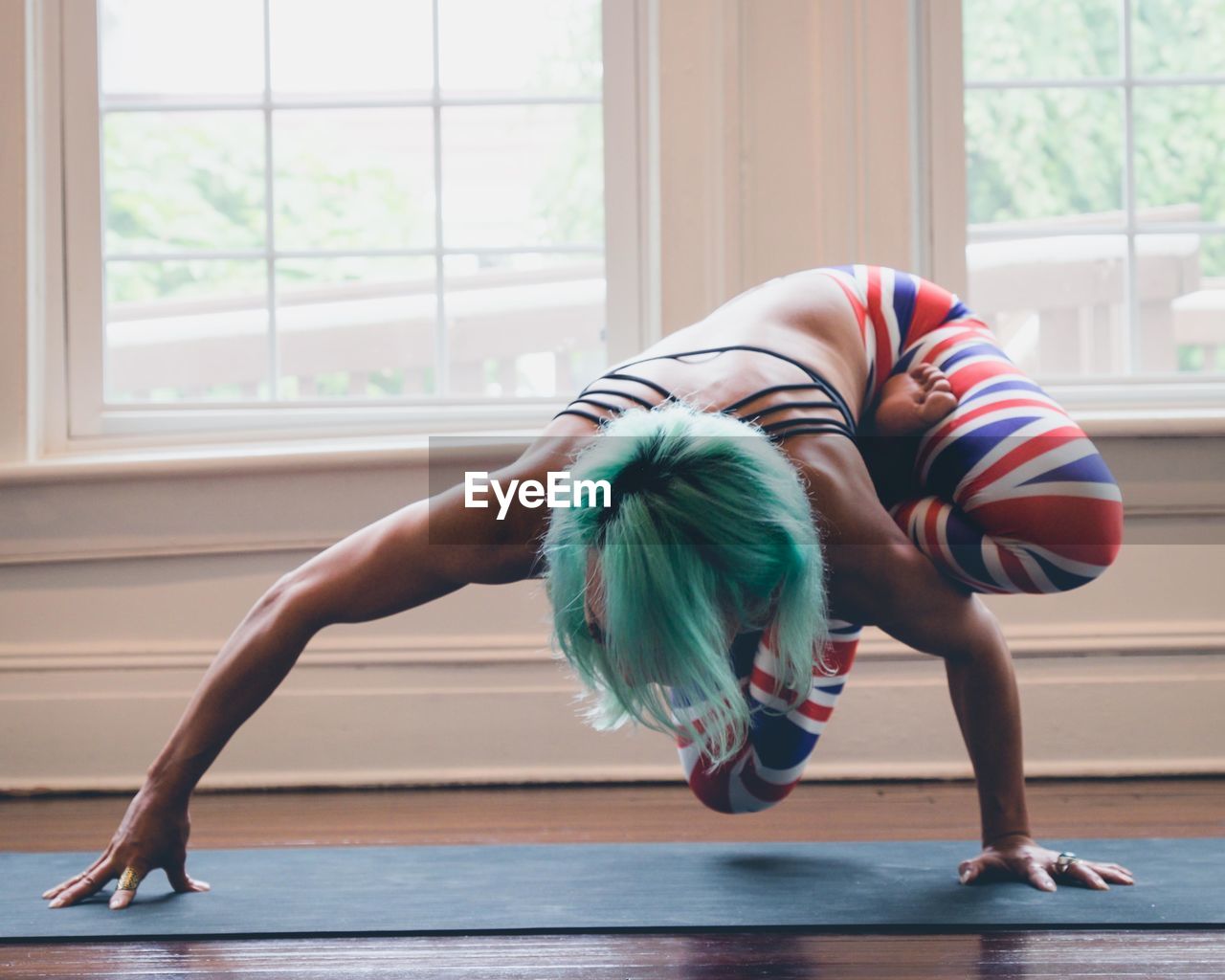 Full length of woman stretching against window