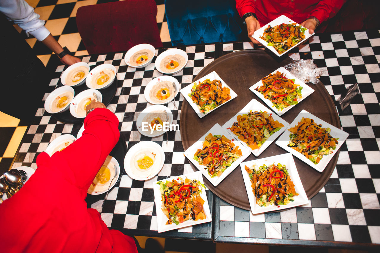Overhead view of people arranging food in plate on table