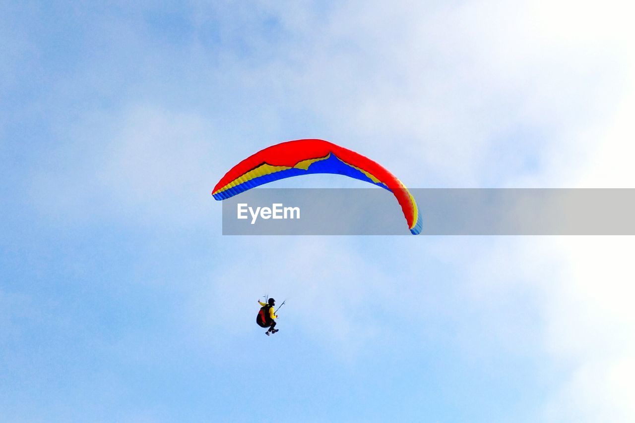 Low angle view of man paragliding against sky