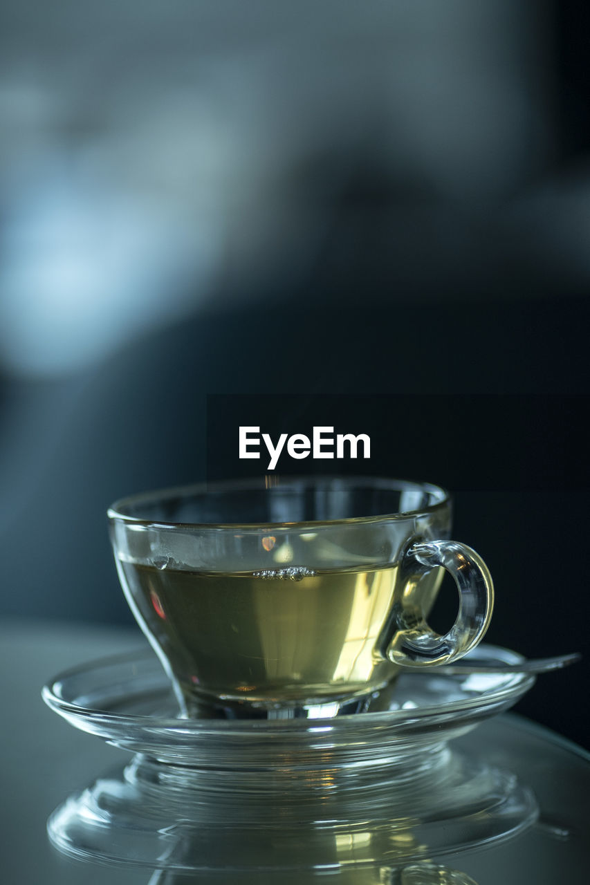 A cup of tea served in the clear glass on the table