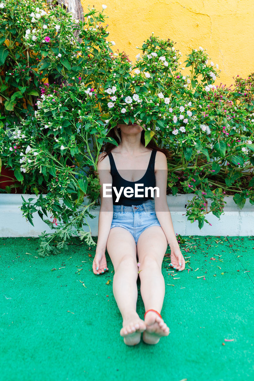 green, one person, plant, full length, front view, leisure activity, women, grass, lifestyles, nature, flower, day, adult, clothing, young adult, casual clothing, outdoors, lawn, growth, sitting, person, relaxation, child, human leg, summer, leaf, female, architecture, plant part