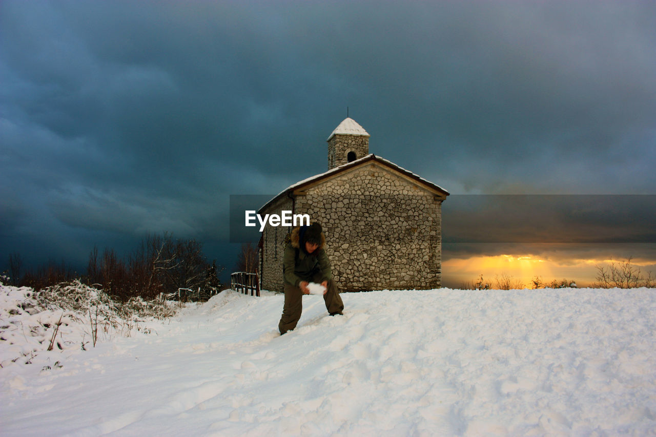 HOUSE ON SNOW COVERED FIELD AGAINST SKY DURING WINTER