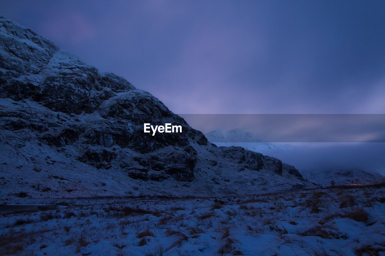 Scenic view of snowcapped mountains against cloudy sky