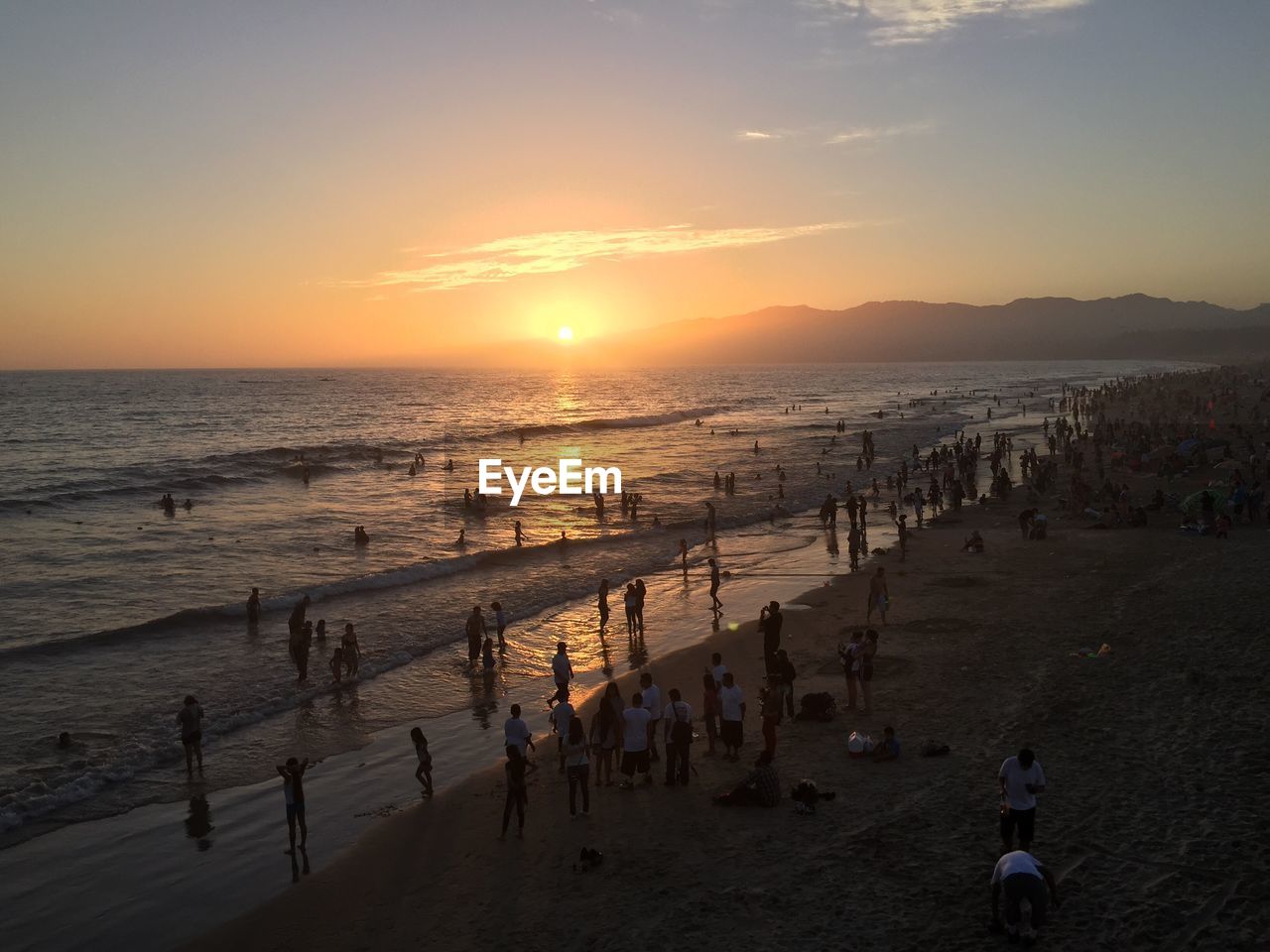 High angle view of people at beach against sky during sunset