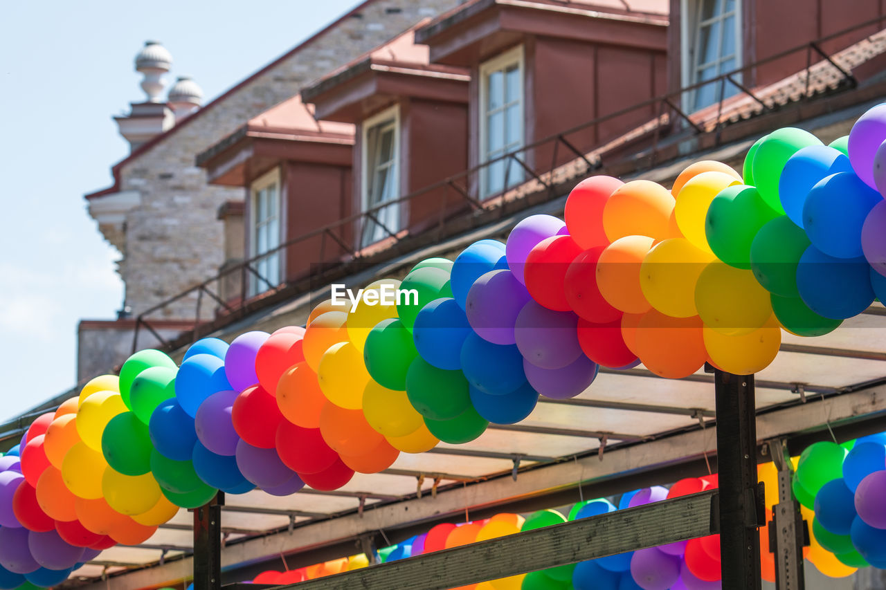 multi colored, architecture, building exterior, built structure, balloon, celebration, decoration, nature, city, building, no people, tradition, day, event, hanging, low angle view, outdoors, sky, toy, vibrant color, lantern, lighting equipment, in a row, large group of objects, variation, traditional festival, yellow, festival