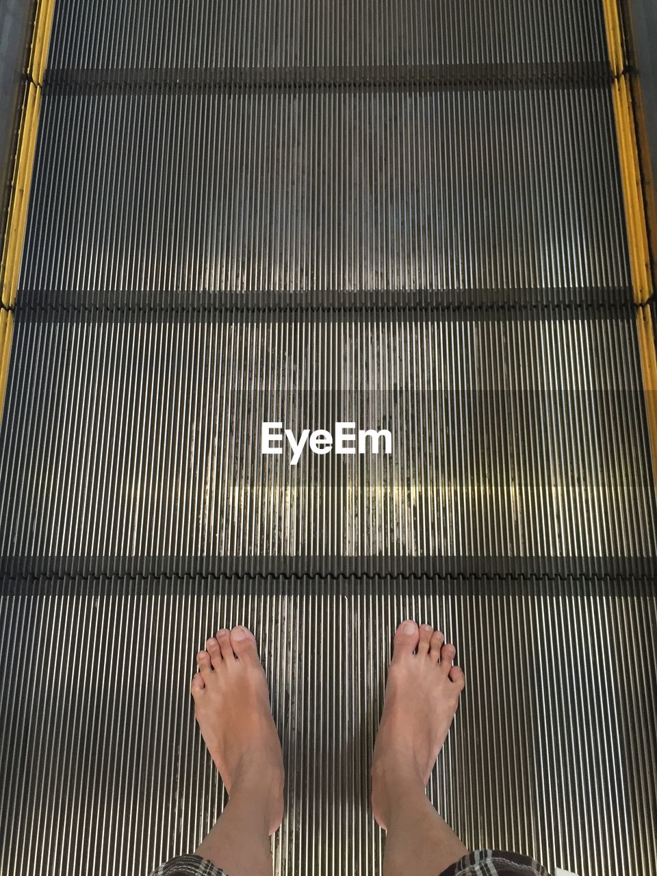 LOW SECTION OF WOMAN STANDING ON ESCALATOR