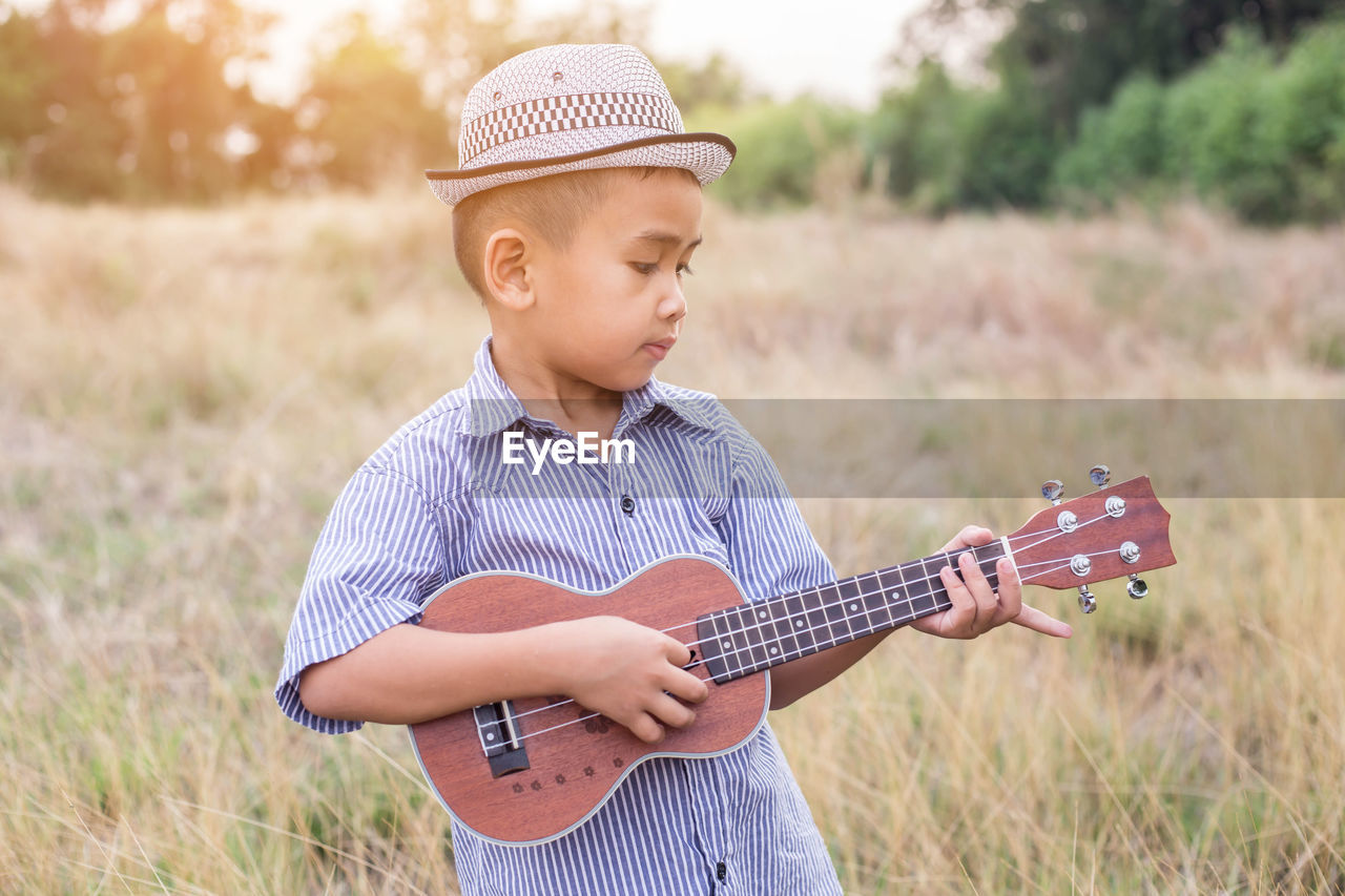 Boy playing ukulele on field