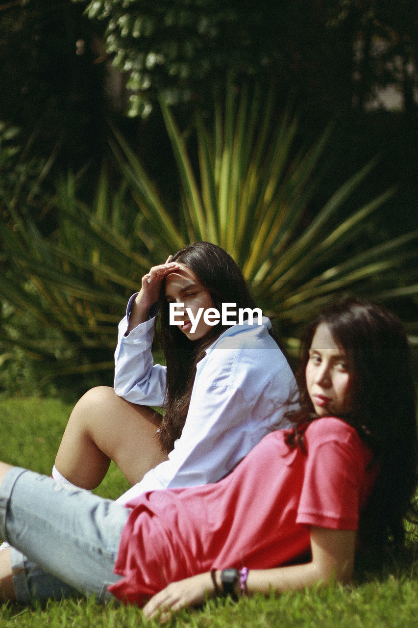 Friends resting on field against trees