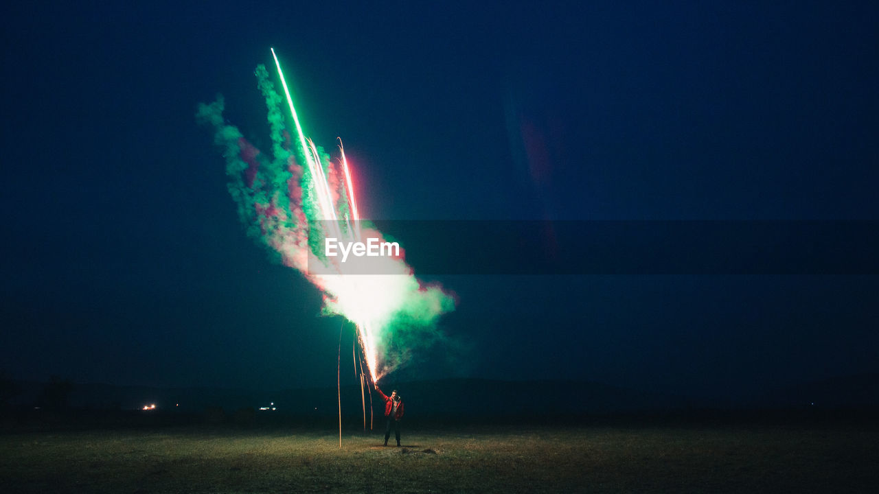 Man holding firework at night against sky