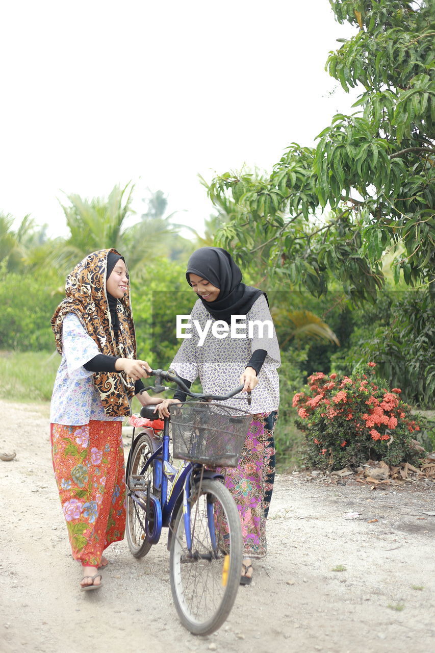 Sisters with bicycle on dirt road