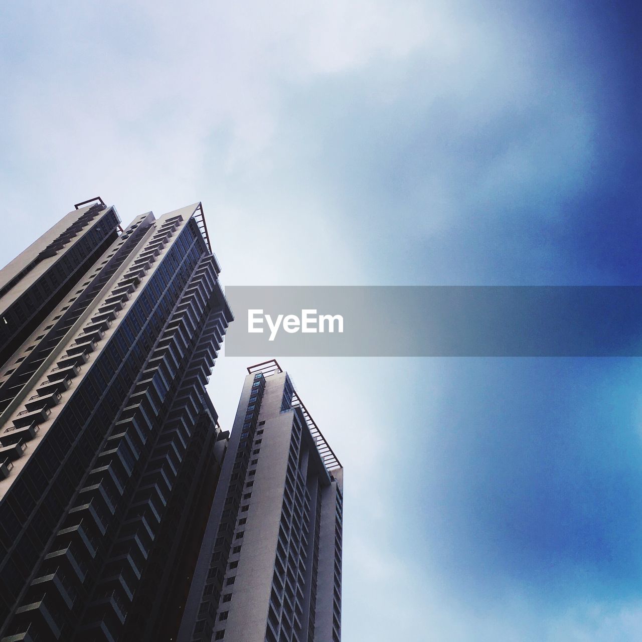 LOW ANGLE VIEW OF MODERN BUILDINGS AGAINST CLOUDY SKY