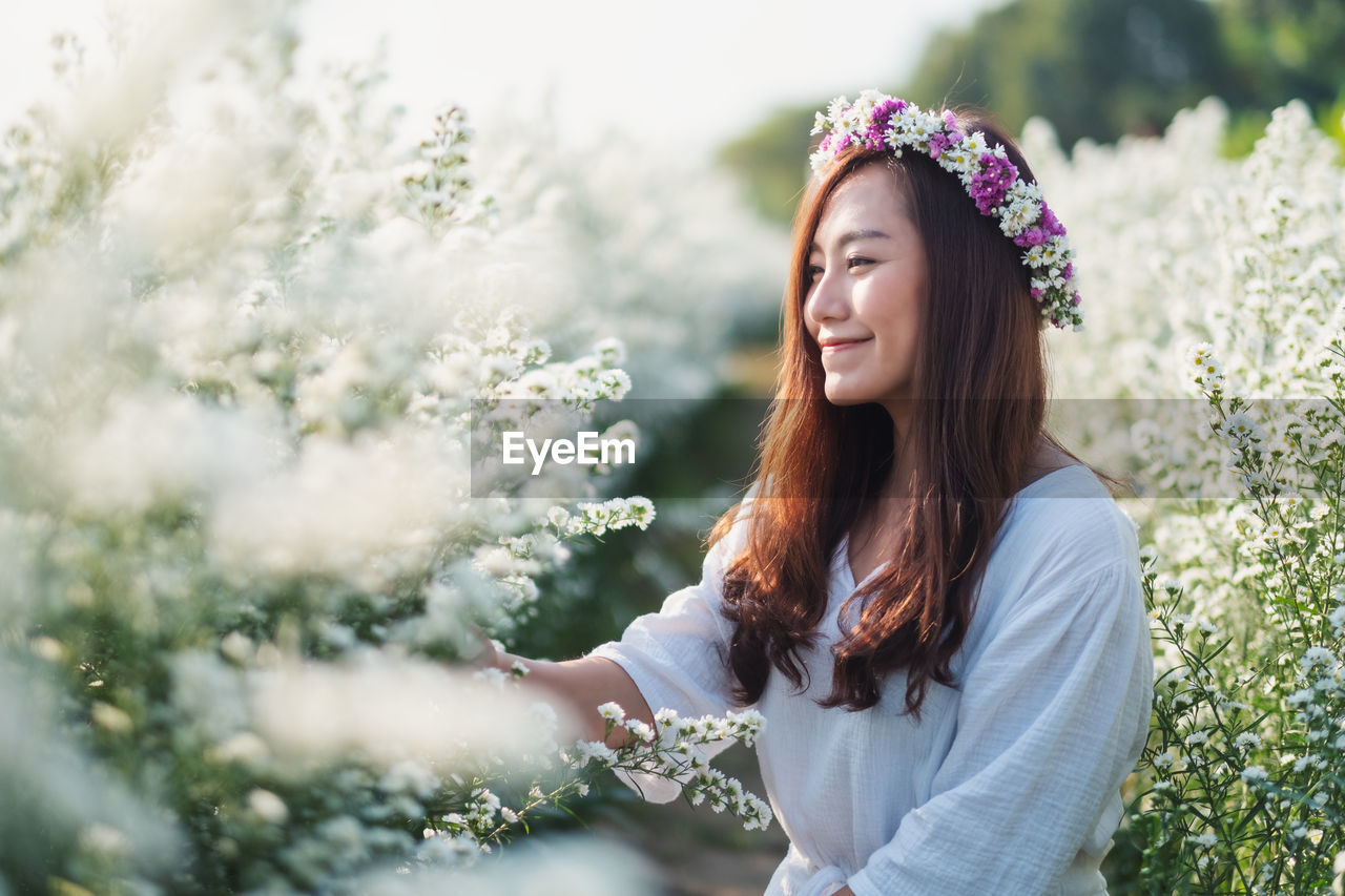 Smiling woman standing by flowering plants