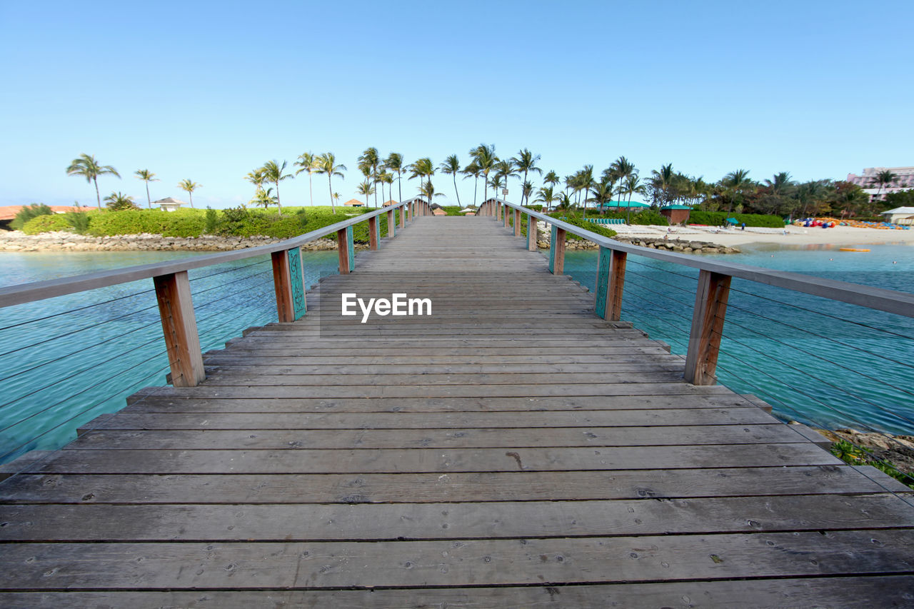 A wooden bridge over water going over to a beach