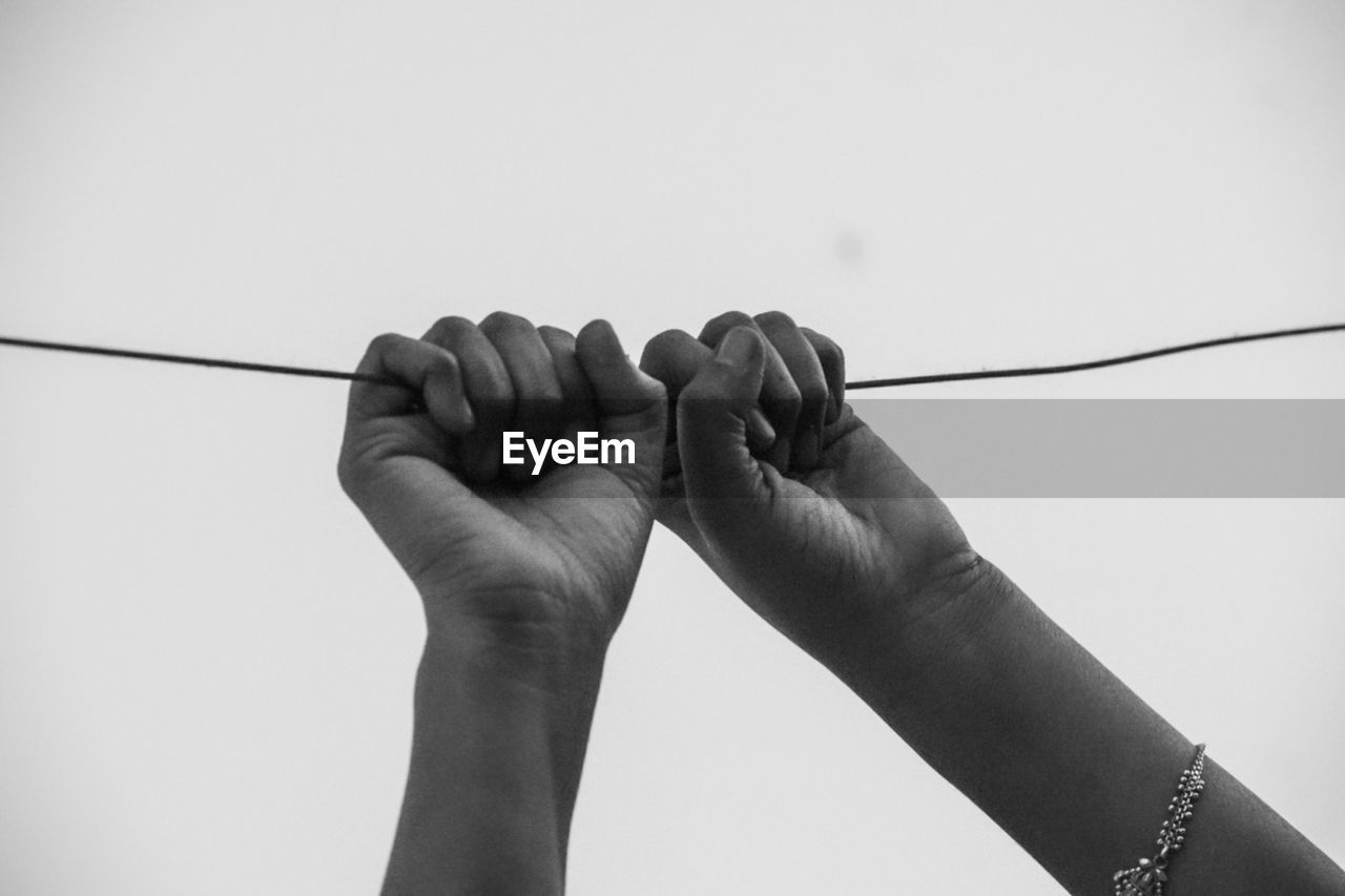 cropped hand of person holding rope against white background