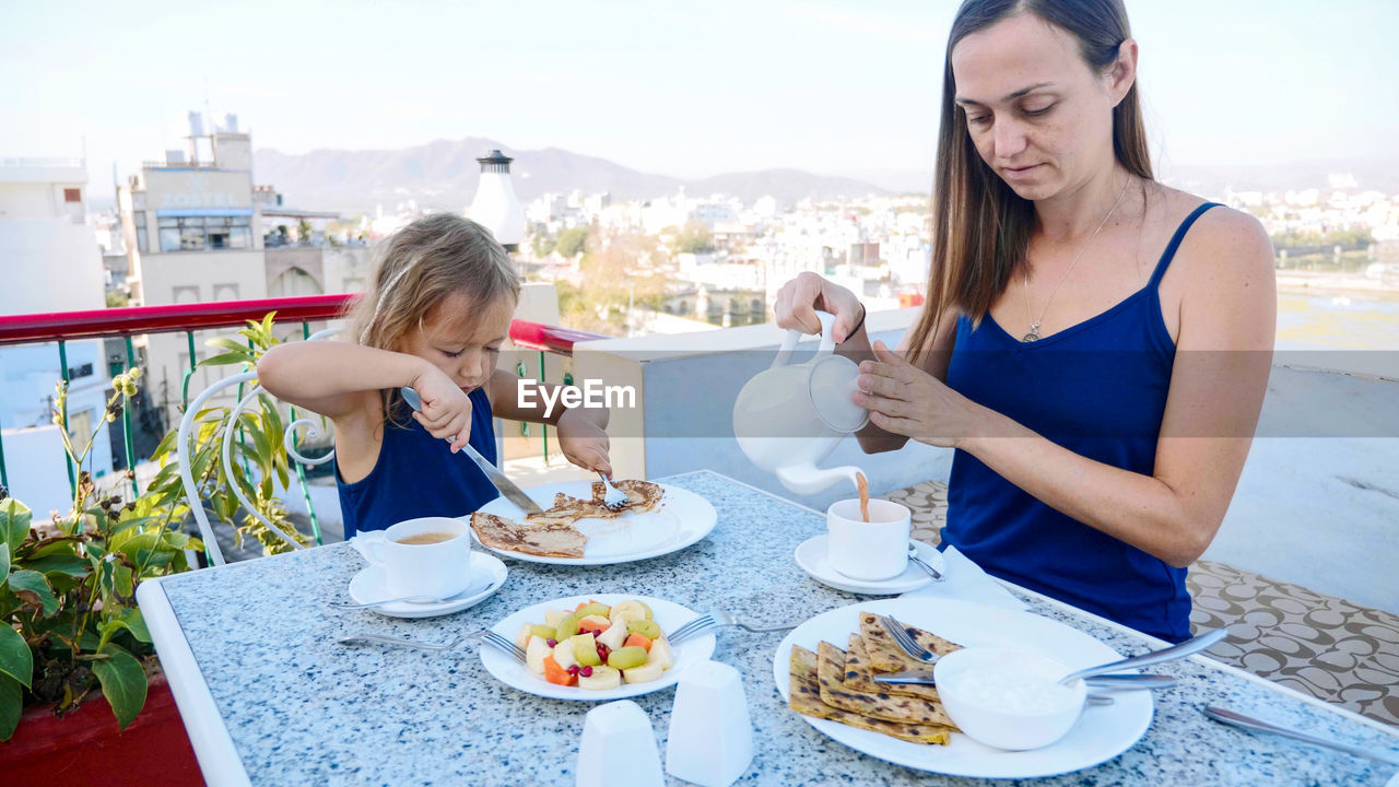 Mother and daughter having breakfast in balcony