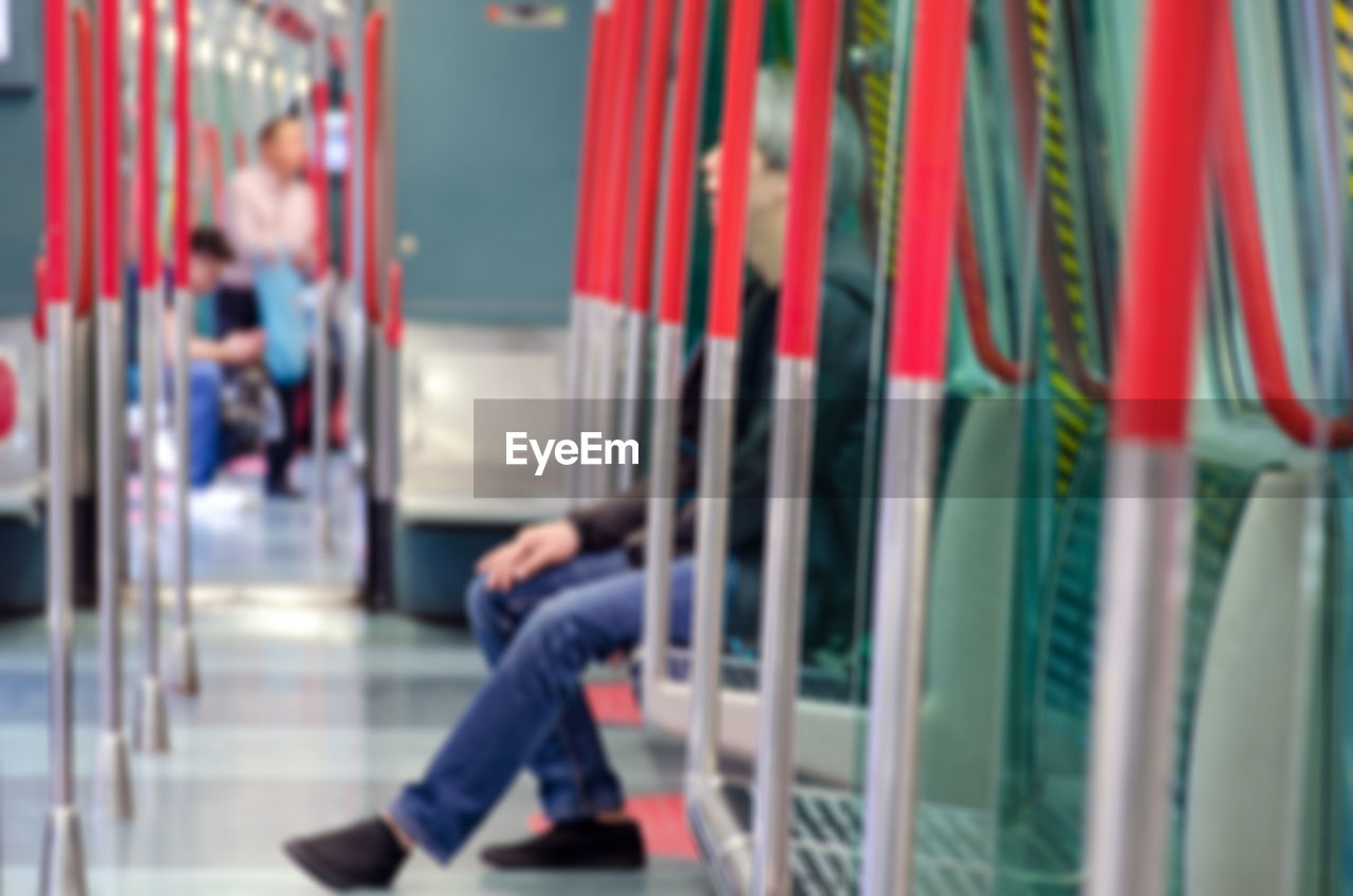Defocused people in a subway car. inside the subway train, seating and handrails