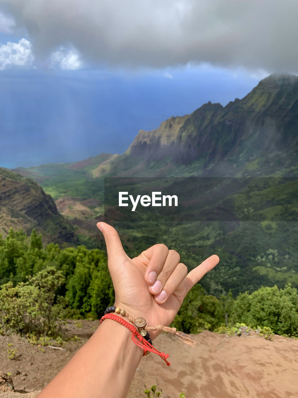 MIDSECTION OF PERSON AGAINST SKY OVER MOUNTAIN