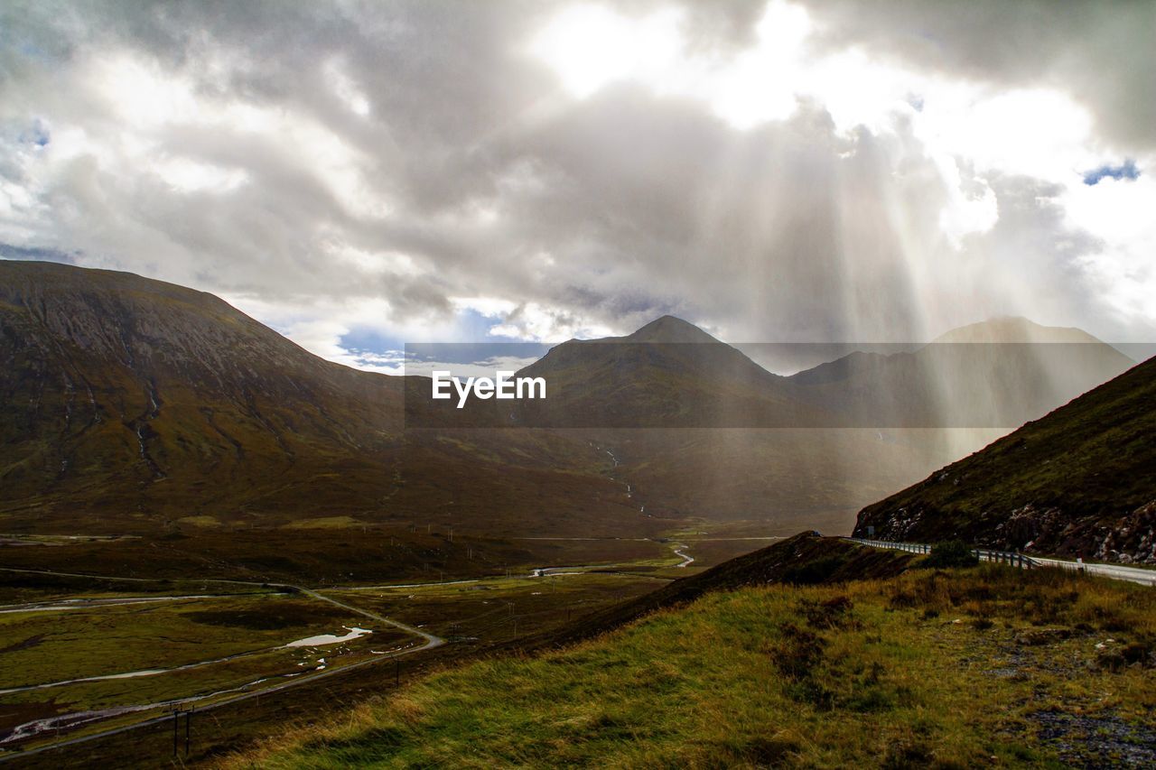 Scenic view of landscape and mountains against cloudy sky