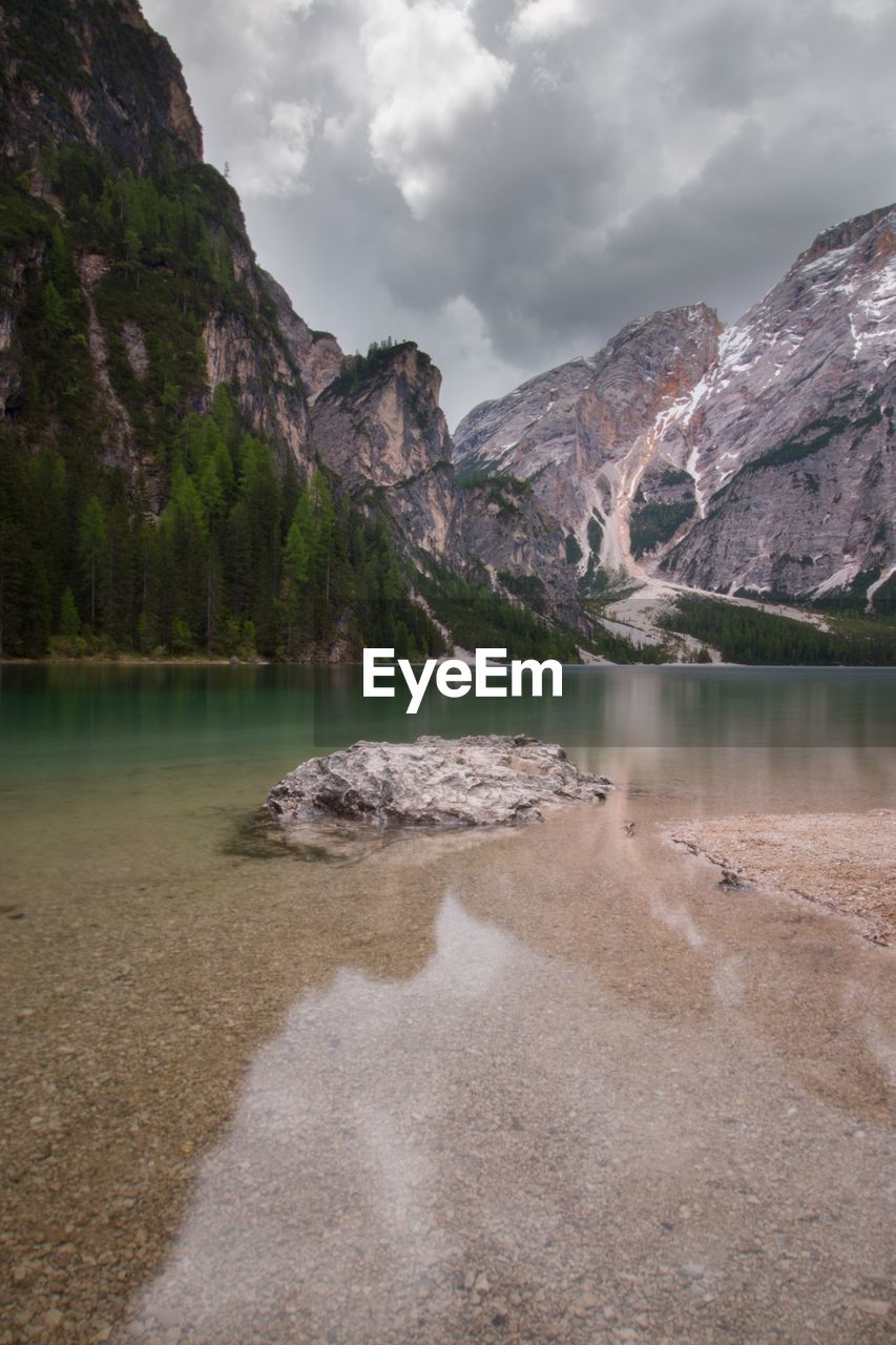 Scenic view of lake and mountains against cloudy sky