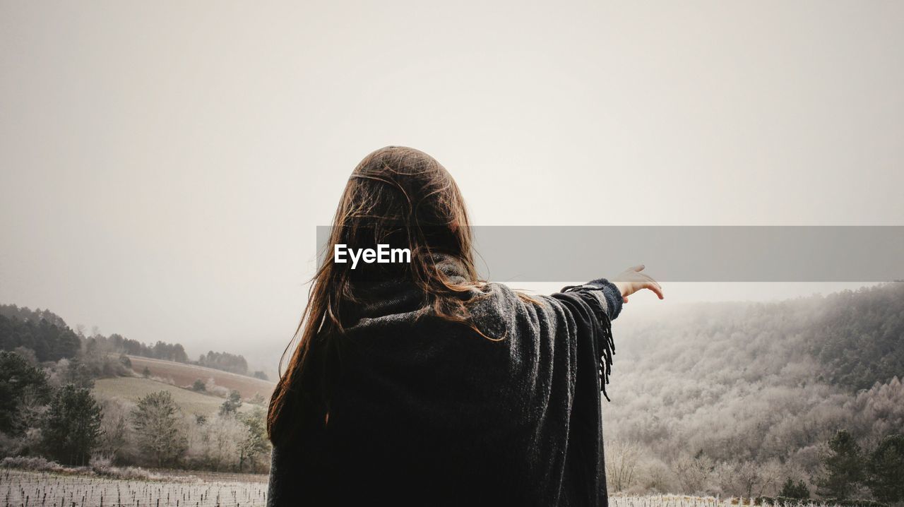 Rear view of woman pointing at clear sky