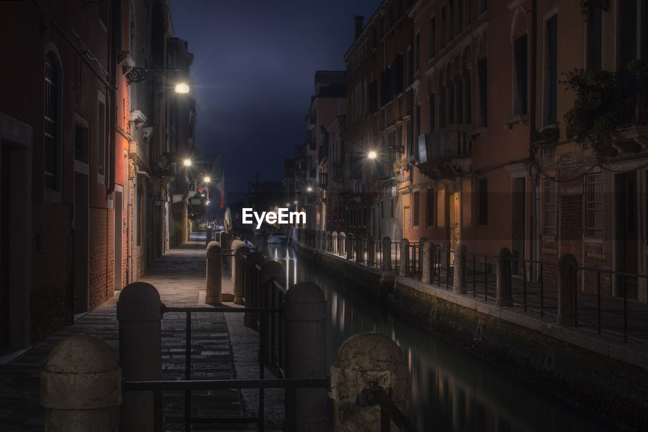 STREET AMIDST BUILDINGS AT NIGHT
