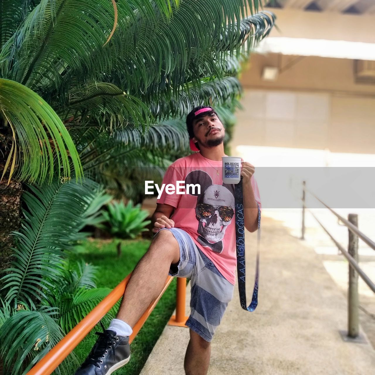 YOUNG MAN STANDING AGAINST PALM TREES