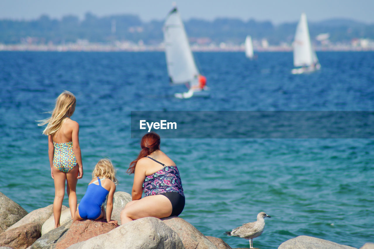 Rear view of people overlooking calm sea