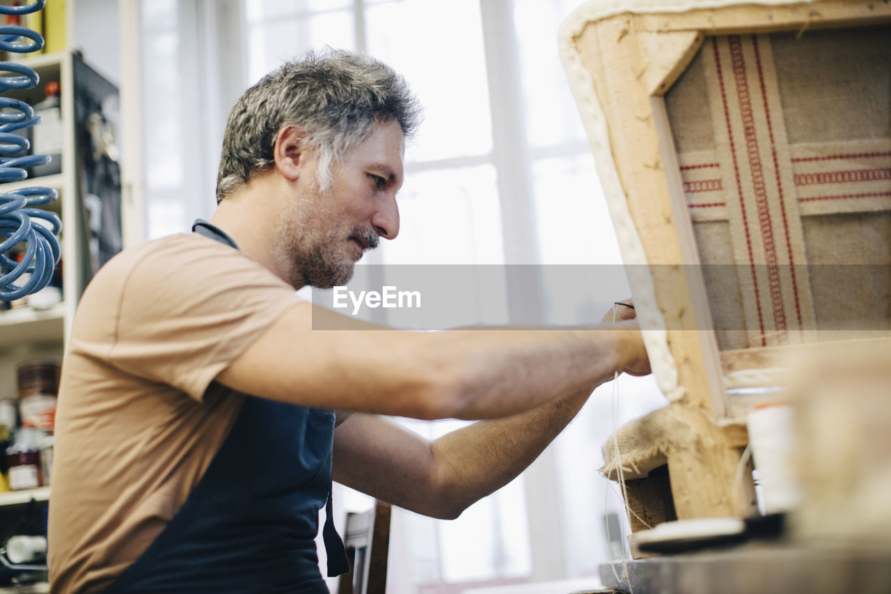 Mature craftsperson making furniture in workshop