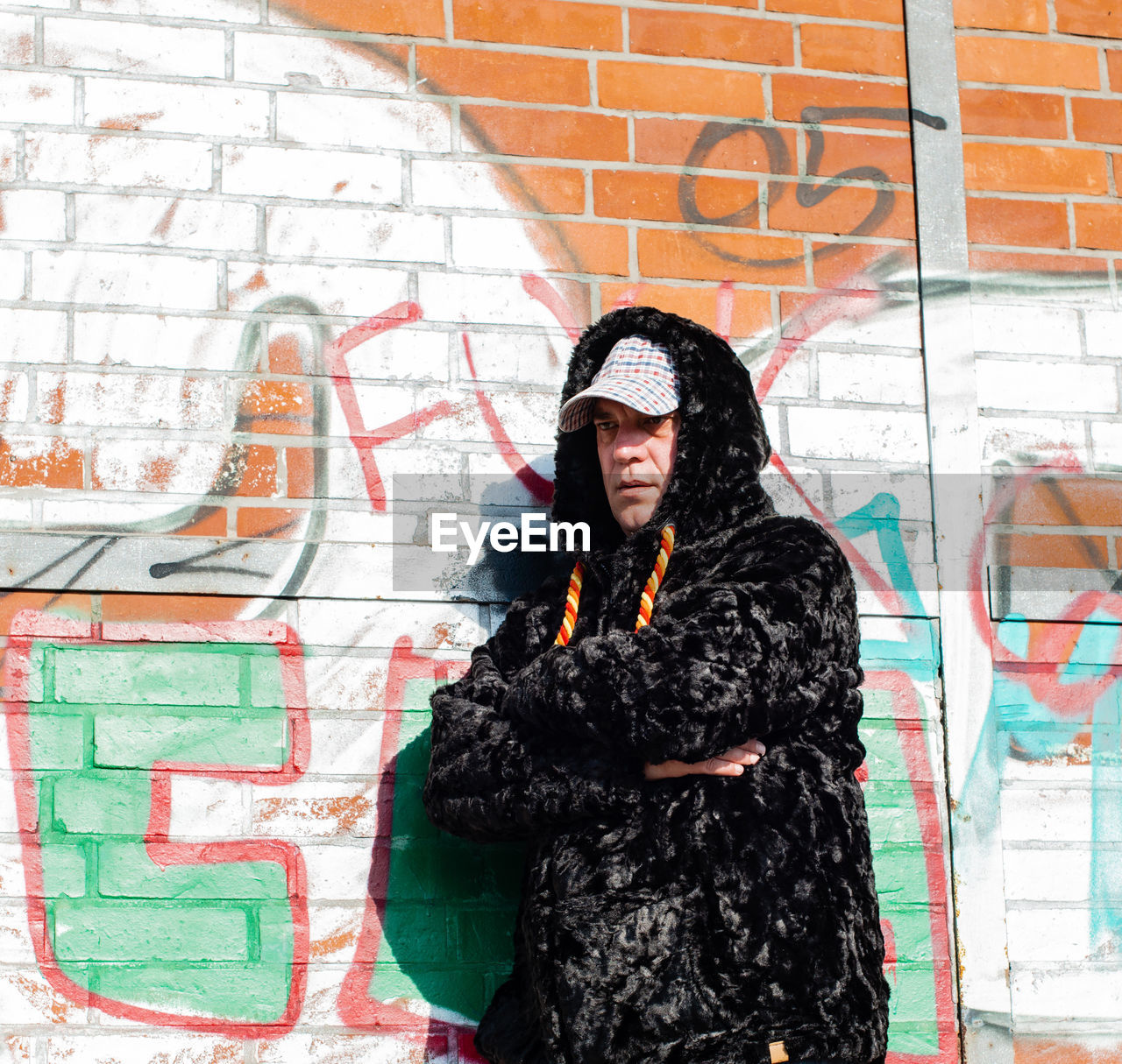 Fashionable mature man standing against graffiti wall