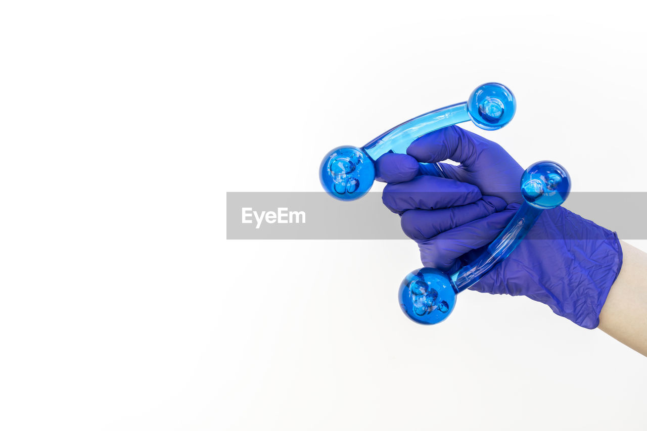 Mockup human gloved hand holds blue acrylic back, leg, neck massage tool. deep tissue massage, thumb