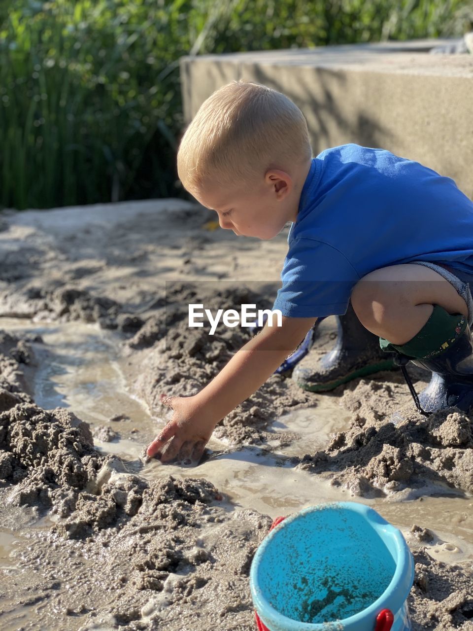 childhood, child, men, one person, sand, full length, nature, land, day, beach, leisure activity, bucket, innocence, toddler, casual clothing, blond hair, blue, lifestyles, outdoors, sunlight, water, looking, summer, sand pail and shovel, cute, container, looking down, standing, holding, person, baby, high angle view, digging, fun, soil