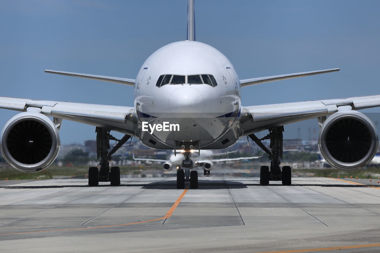 Airplane on runway against clear blue sky