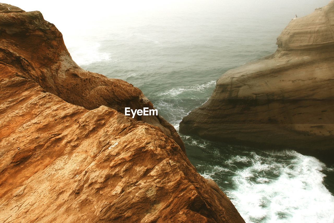 Scenic view of sea and rock formations during foggy weather