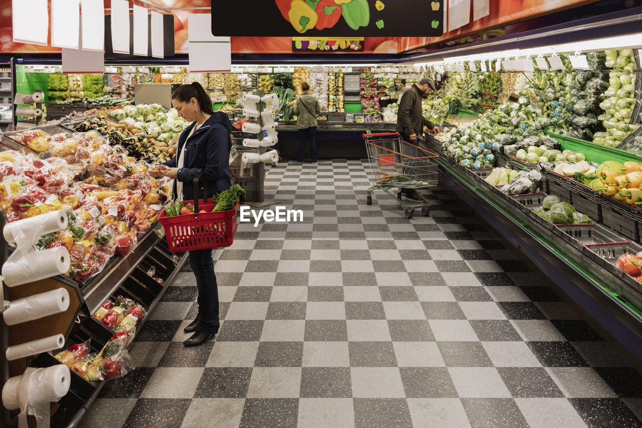 People buying vegetables while standing in supermarket