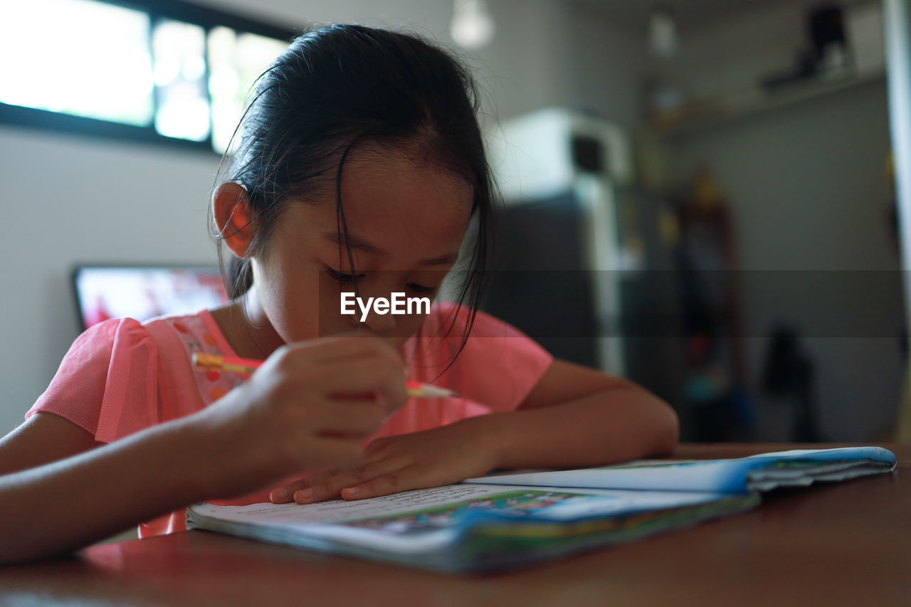 Close-up of girl with hands on table