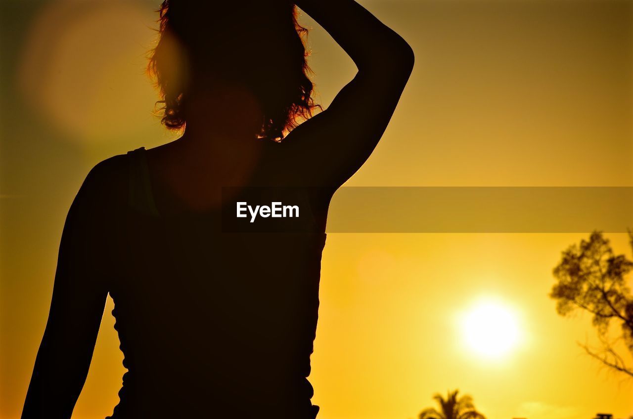 Woman standing against orange sky