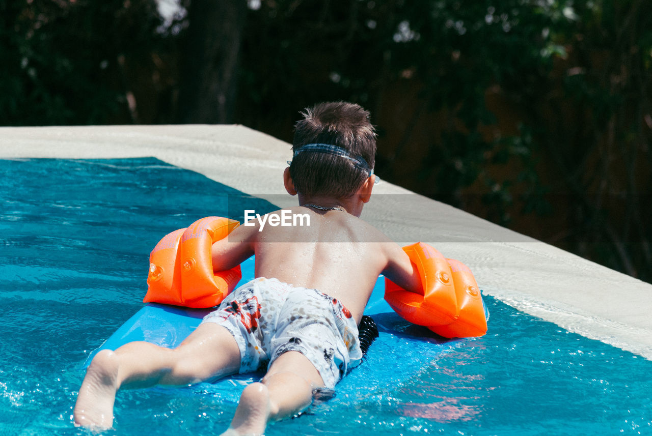 Rear view of shirtless boy in swimming pool