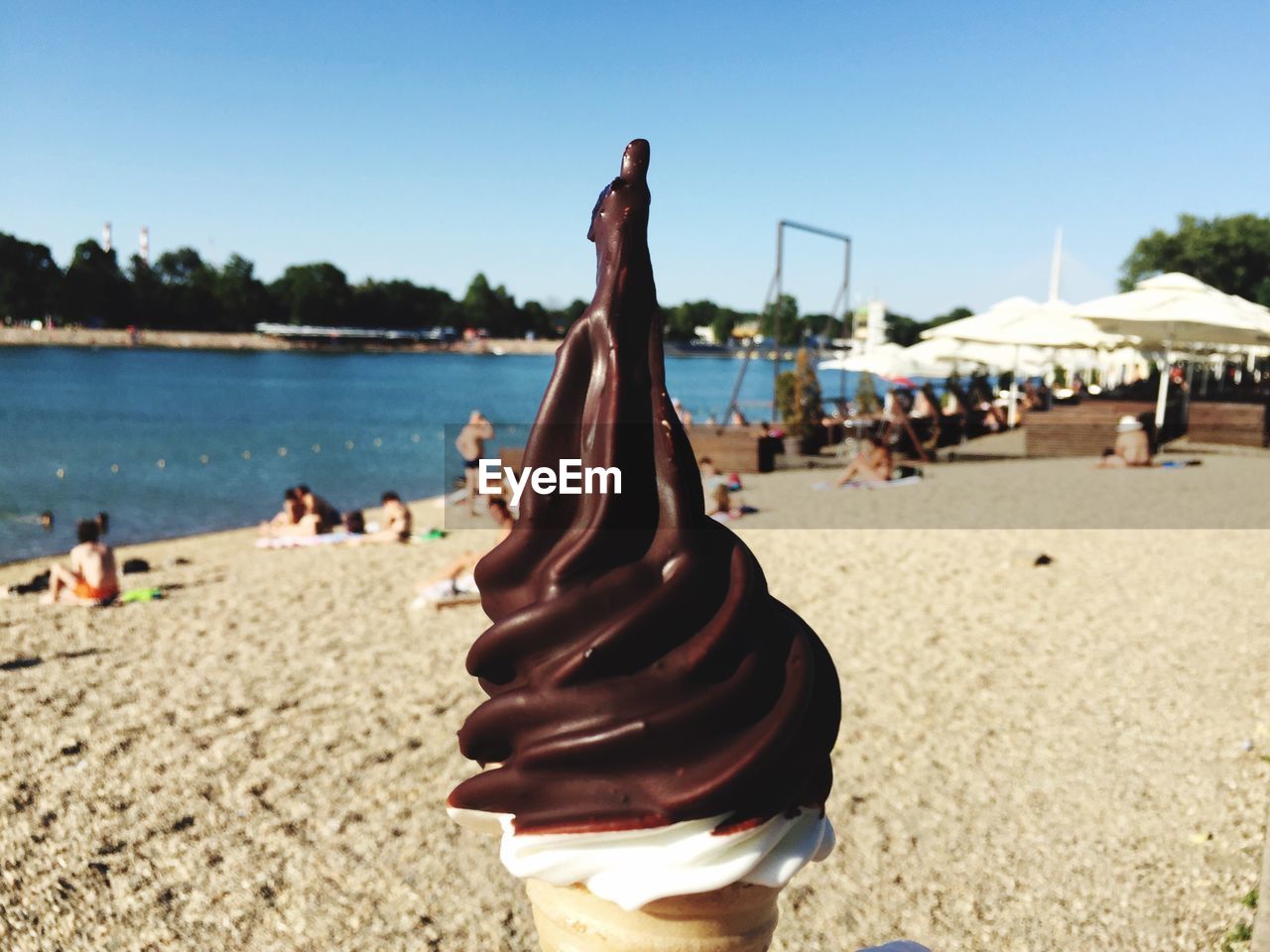 Close-up of ice cream cone at beach against sky on sunny day