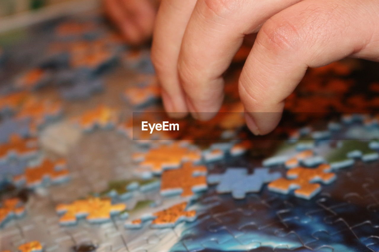 Cropped image of hands solving jigsaw puzzle