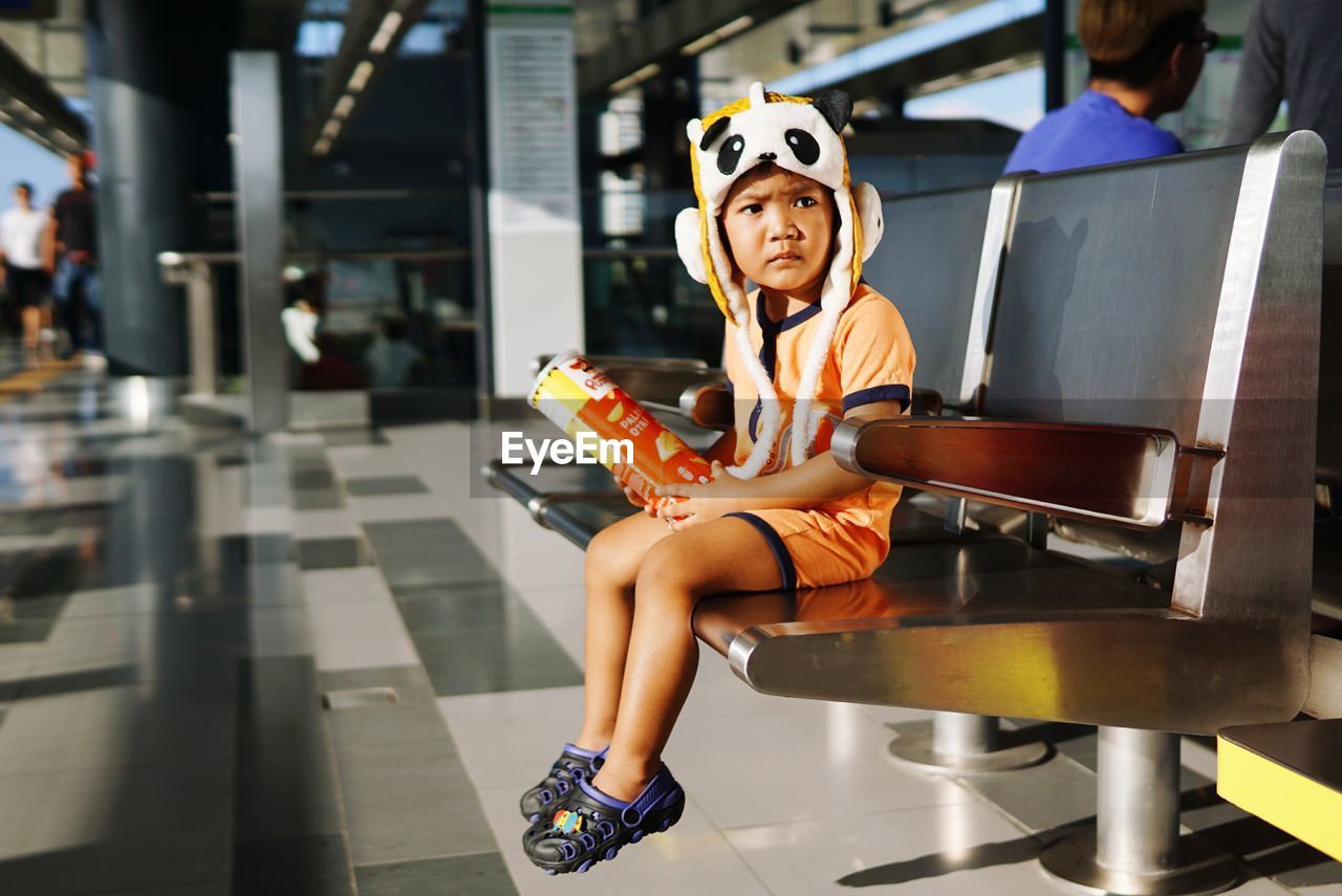 Cut boy sitting on bench at railroad station platform