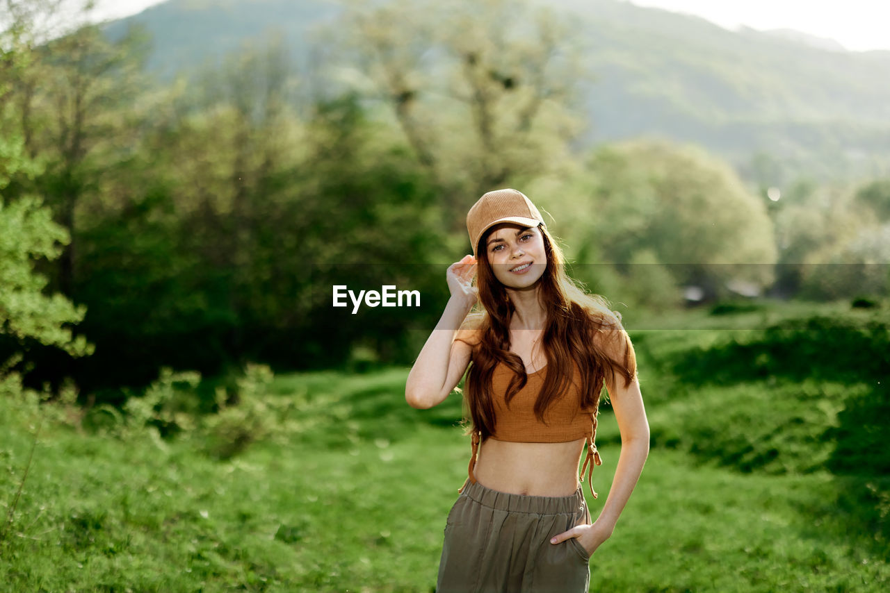 portrait of young woman wearing sunglasses standing on field