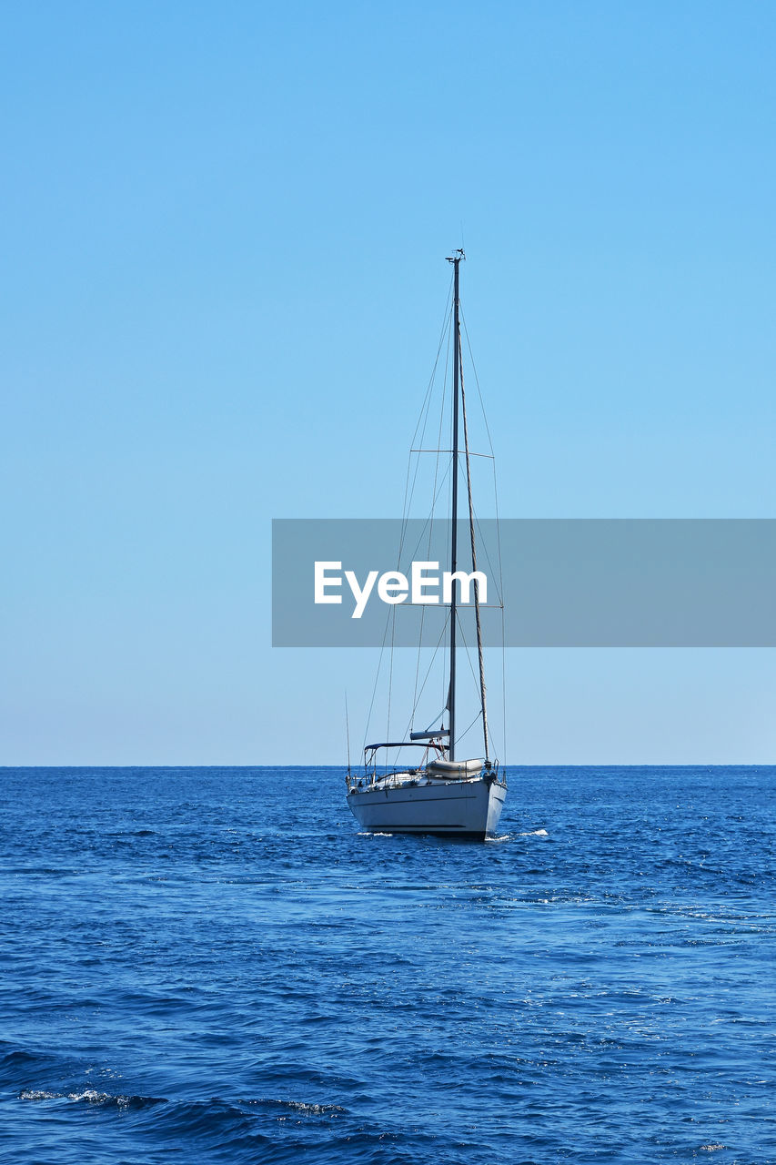 SAILBOAT SAILING IN SEA AGAINST CLEAR SKY