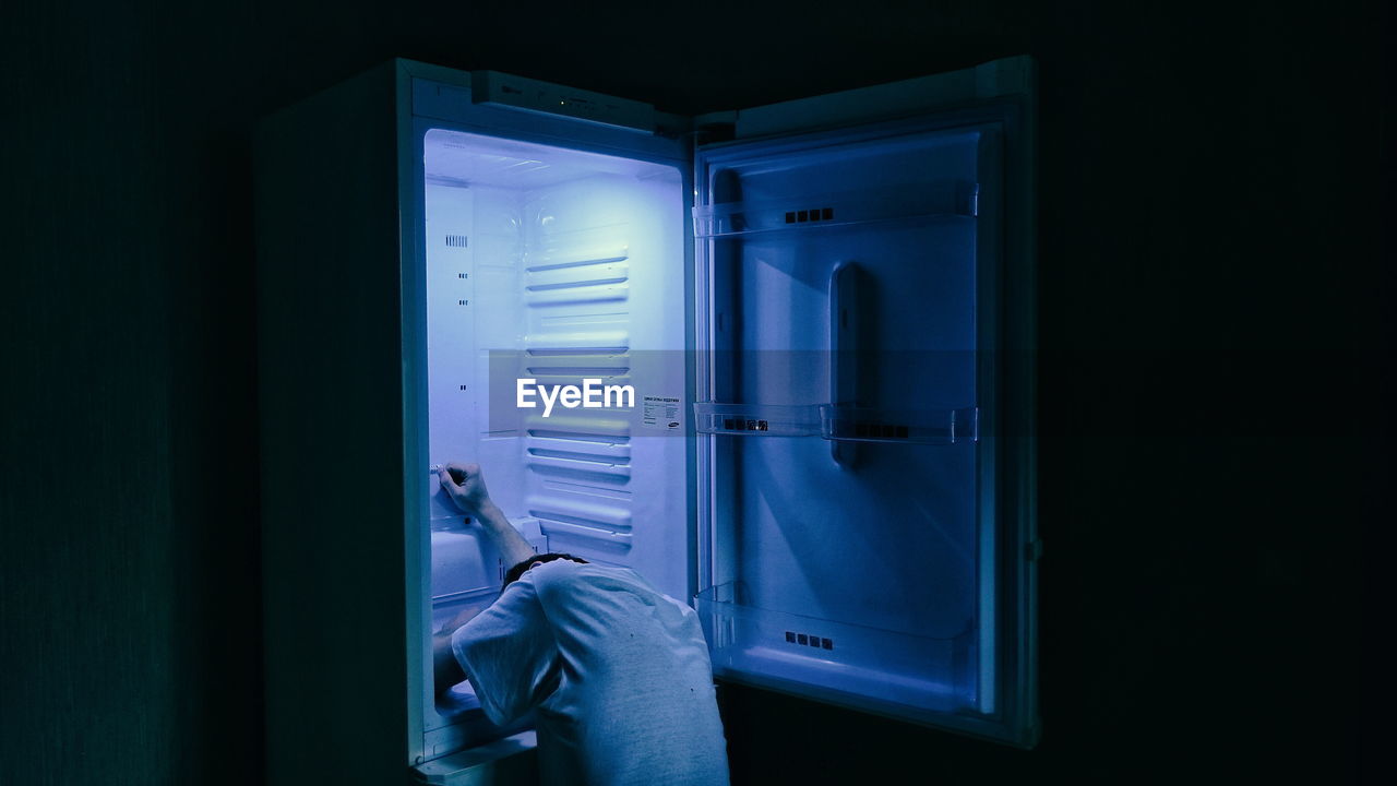 Man sleeping in refrigerator at home