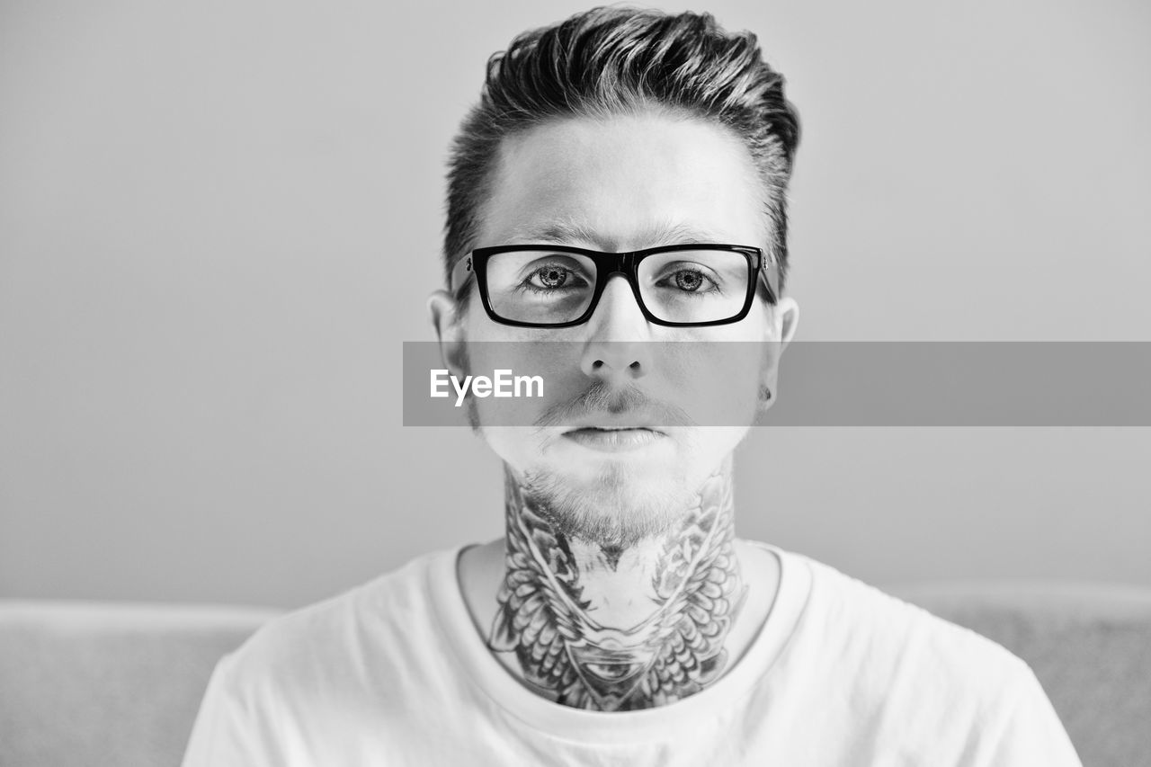 Portrait of young man wearing eyeglasses against gray background