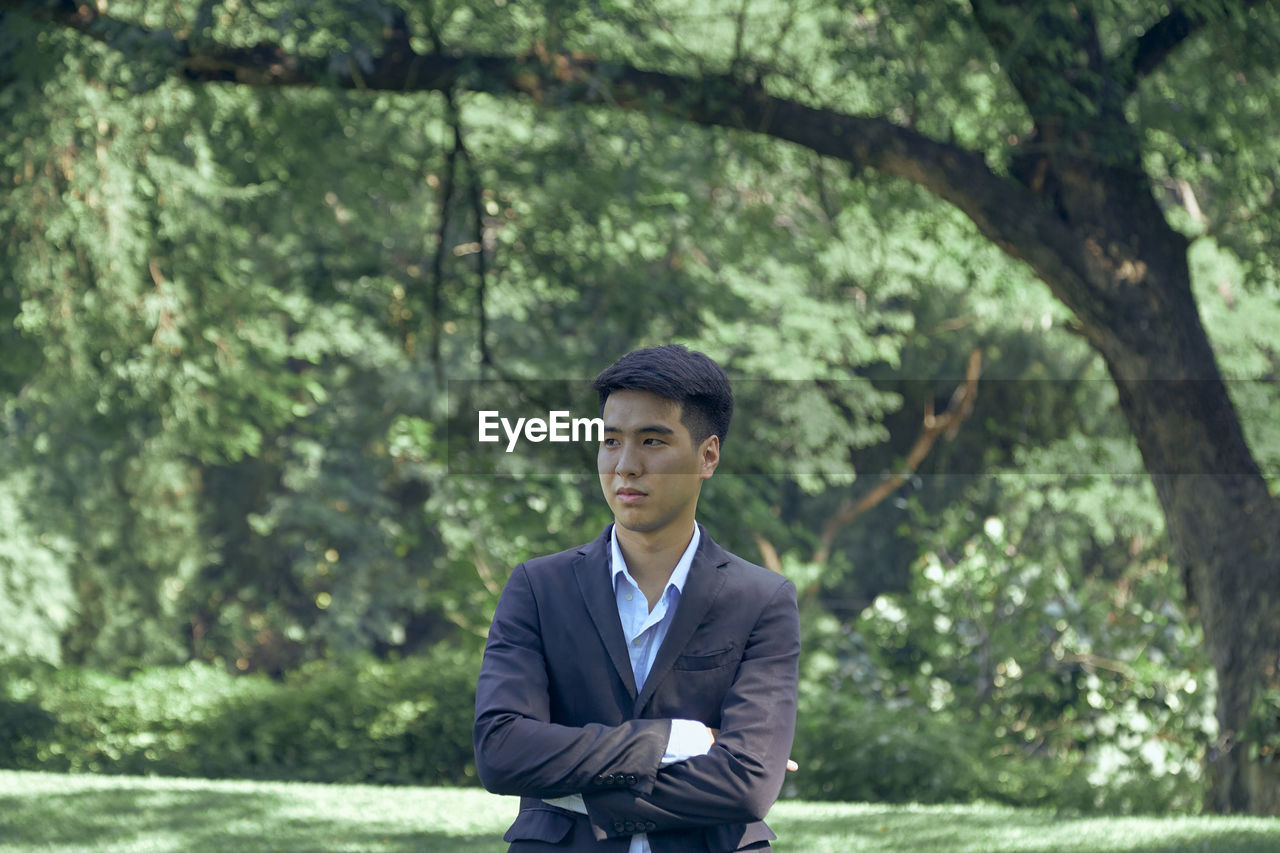 A handsome young asian businessman standing in the park