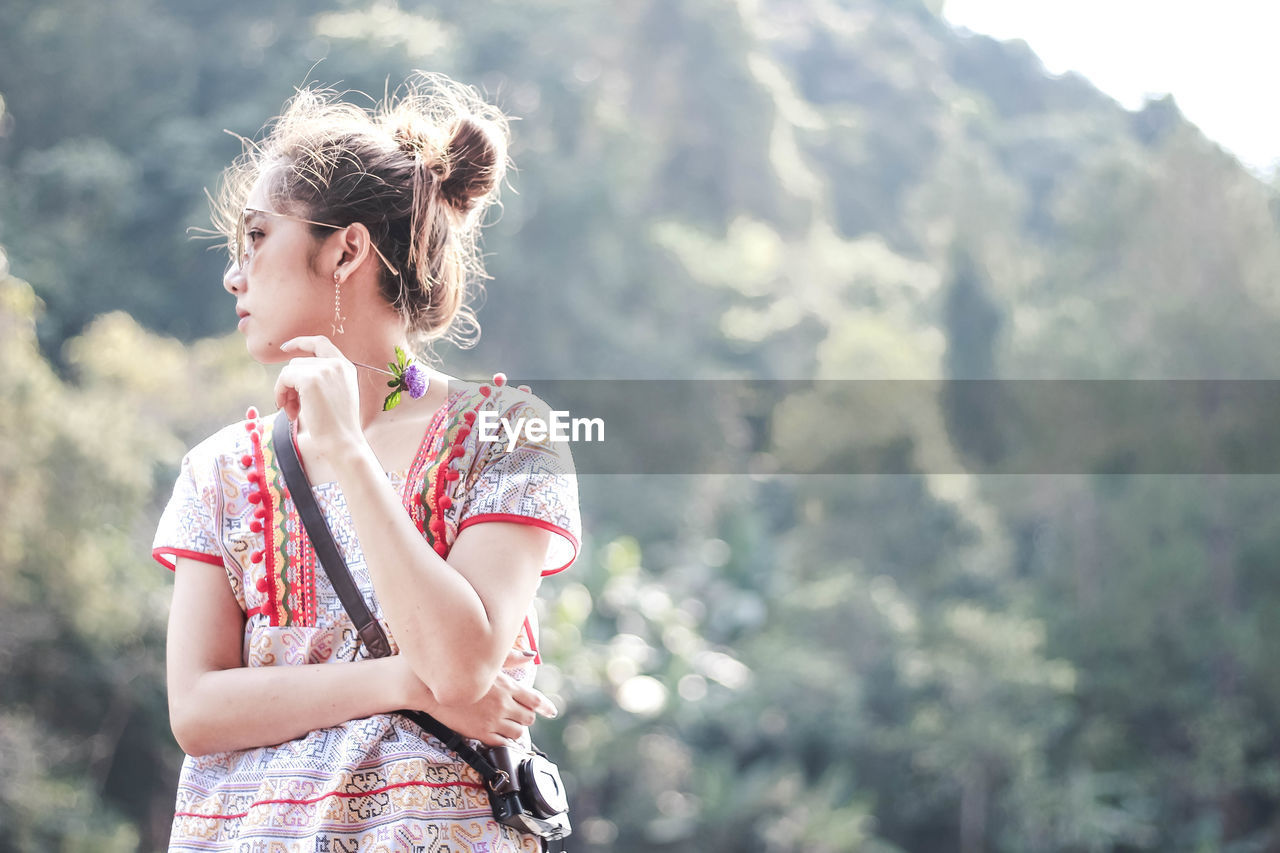 Young woman wearing sunglasses standing against mountain