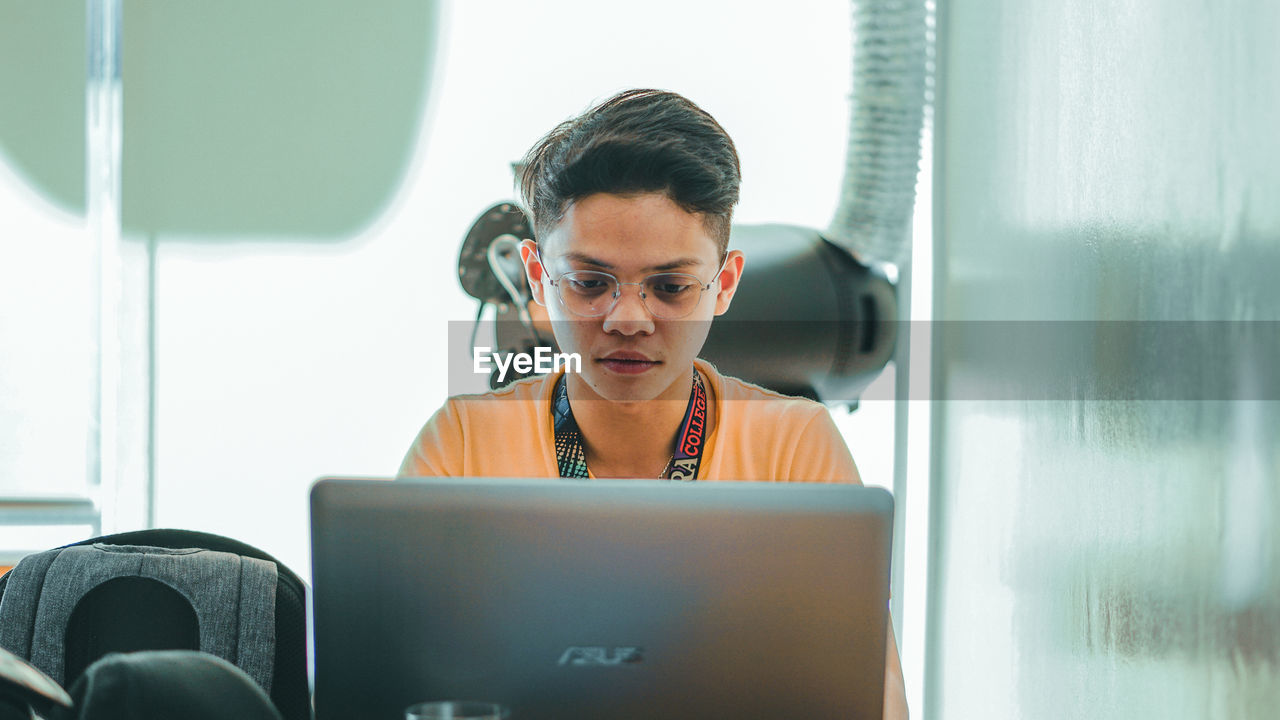 PORTRAIT OF SENIOR MAN USING MOBILE PHONE IN OFFICE