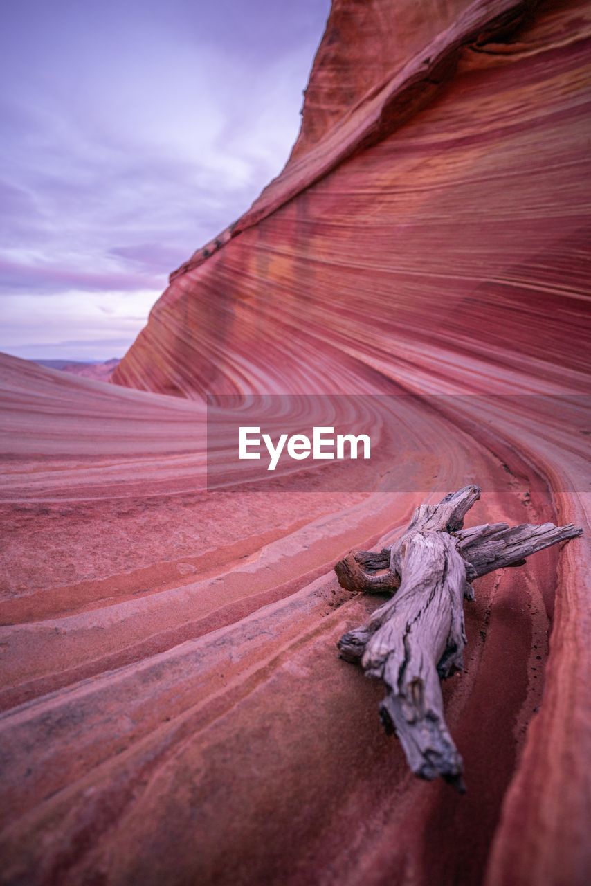 Driftwood on rock formation against sky